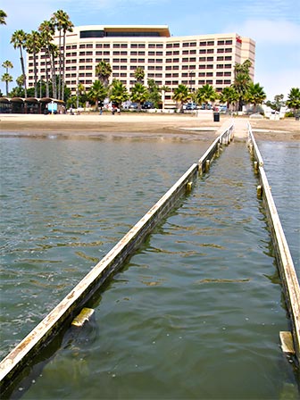 Wheelchair Railing at Mother's Beach in Marina del Rey. The wooden railing is seen here at high tide. The Marriott hotel is in the background. [Photo Credit: LAtourist.com]