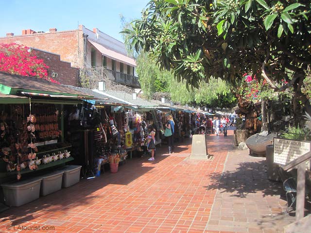 Shops near Avila Adobe on Olvera Street. There are dozens of stands selling souvenirs, shirts, hats, trinkets and handmade goods. Some of the buildings house museums, while others serve as restaurants and stores (<a target=
