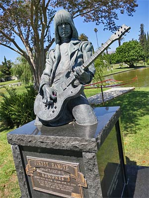 Johnny Ramone's Marker at Hollywood Forever Cemetery. The Hollywood Sign is faintly visible under the neck of the guitar. You can leave guitar picks in Johnny's hand. [Photo Credit: LAtourist.com]